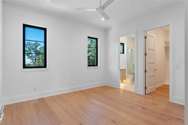 unfurnished bedroom featuring baseboards, a spacious closet, crown molding, light wood-type flooring, and recessed lighting