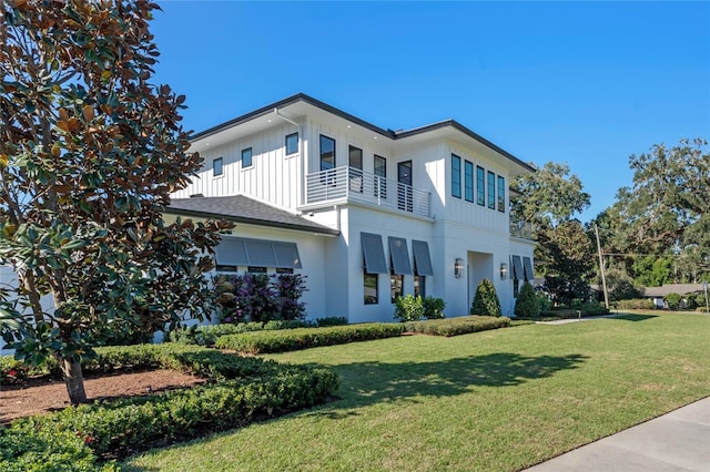 exterior space featuring board and batten siding, a front yard, and a balcony