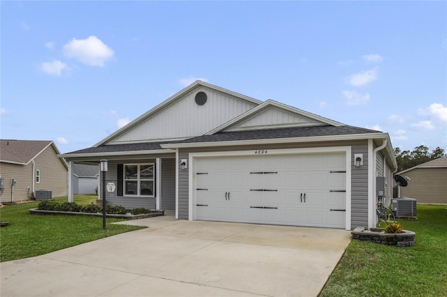 ranch-style home featuring a garage, a front lawn, and central air condition unit