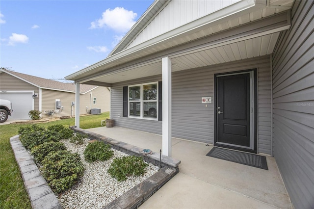 entrance to property featuring a porch, a garage, and central AC