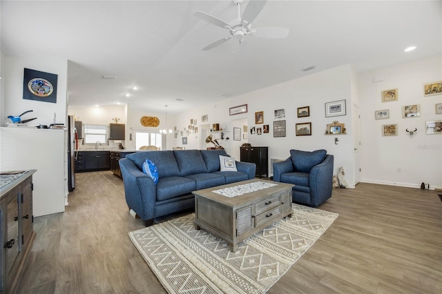 living room featuring hardwood / wood-style floors, ceiling fan with notable chandelier, and sink