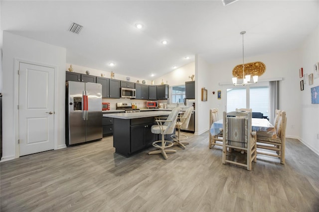 kitchen featuring a center island, hanging light fixtures, light hardwood / wood-style floors, lofted ceiling, and appliances with stainless steel finishes