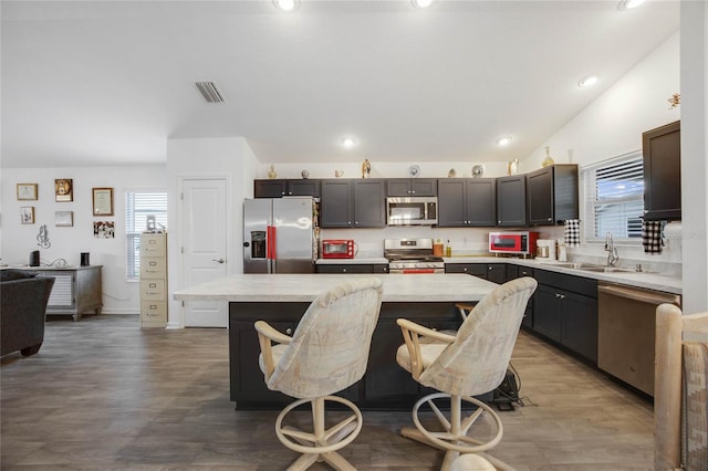 kitchen featuring sink, stainless steel appliances, a breakfast bar area, dark brown cabinets, and a kitchen island