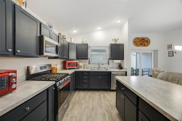 kitchen featuring stainless steel appliances, vaulted ceiling, light hardwood / wood-style floors, and sink