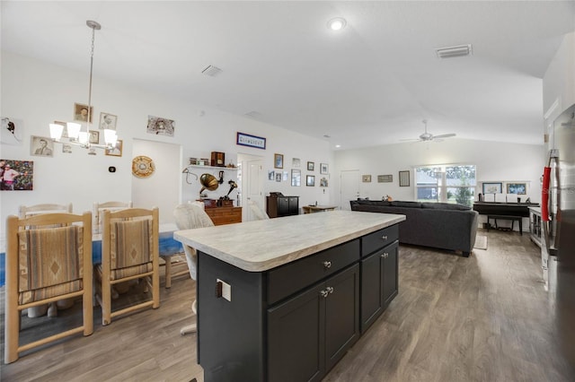 kitchen with ceiling fan, a center island, dark hardwood / wood-style floors, vaulted ceiling, and decorative light fixtures