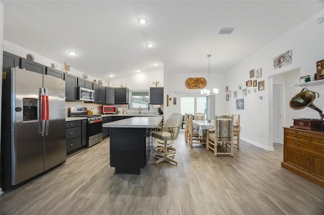 kitchen featuring appliances with stainless steel finishes, vaulted ceiling, pendant lighting, a center island, and a breakfast bar area