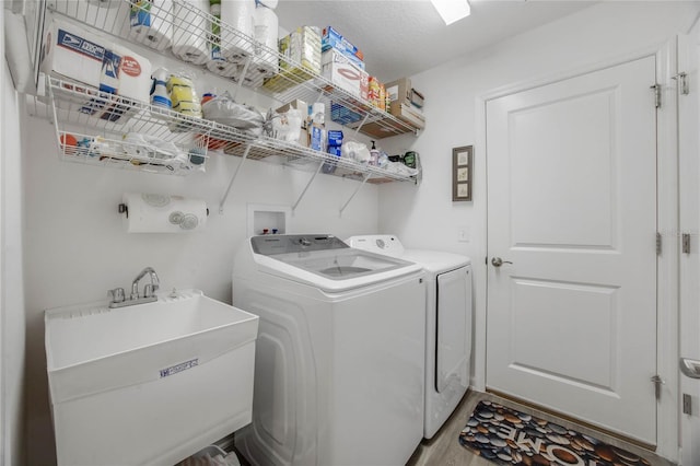 laundry area featuring washer and dryer, a textured ceiling, hardwood / wood-style flooring, and sink