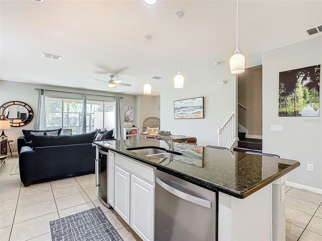 kitchen with white cabinetry, sink, hanging light fixtures, stainless steel dishwasher, and a center island with sink