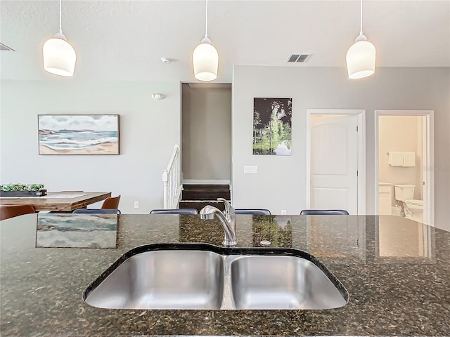 kitchen with sink, hanging light fixtures, and dark stone counters