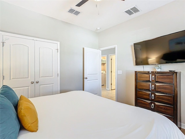 bedroom with ceiling fan, light tile patterned floors, washer / clothes dryer, and a closet