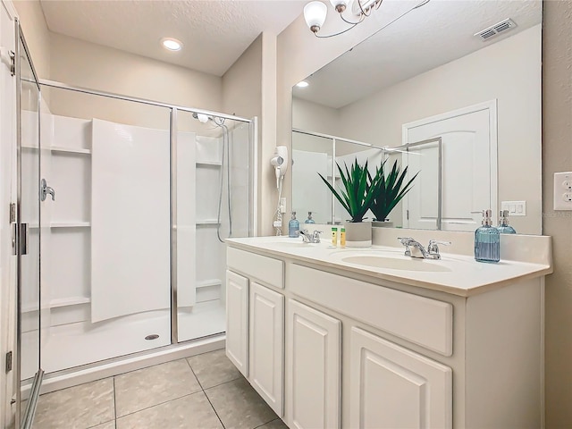 bathroom with a textured ceiling, vanity, tile patterned floors, and walk in shower