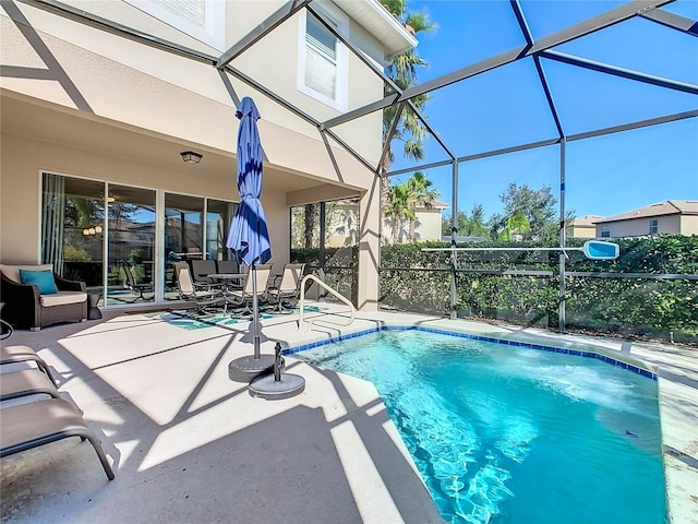 view of pool with glass enclosure and a patio