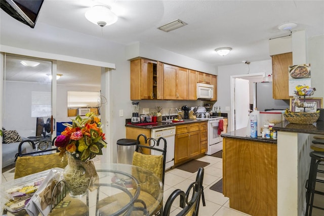 kitchen with kitchen peninsula, a breakfast bar, white appliances, sink, and light tile patterned flooring