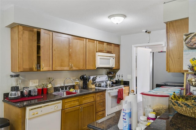 kitchen with a textured ceiling, white appliances, dark stone countertops, and sink