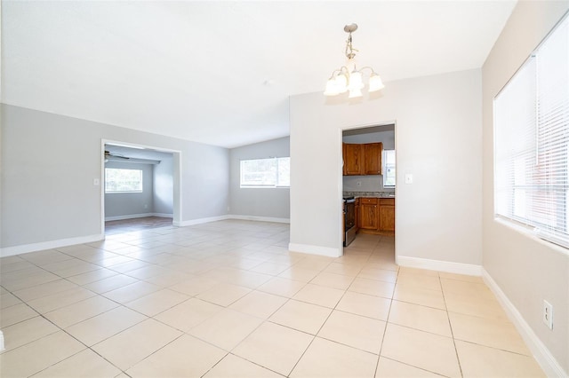 unfurnished room with plenty of natural light, light tile patterned flooring, and an inviting chandelier