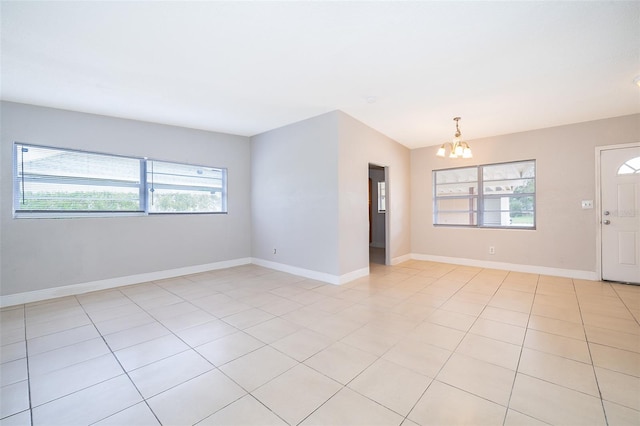 tiled spare room with a chandelier