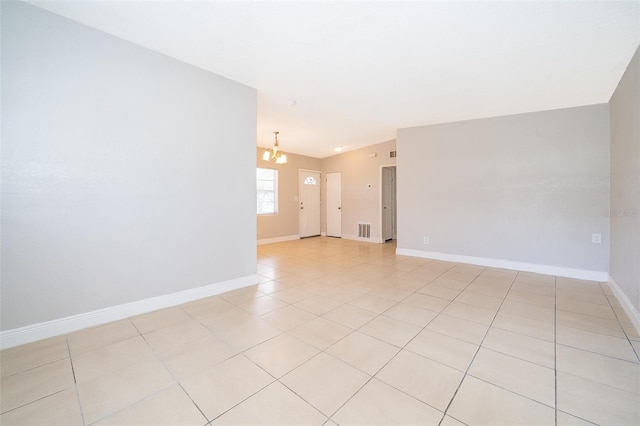 empty room featuring light tile patterned flooring and a notable chandelier