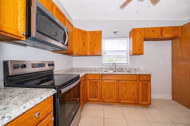 kitchen with light stone countertops, appliances with stainless steel finishes, light tile patterned floors, and sink