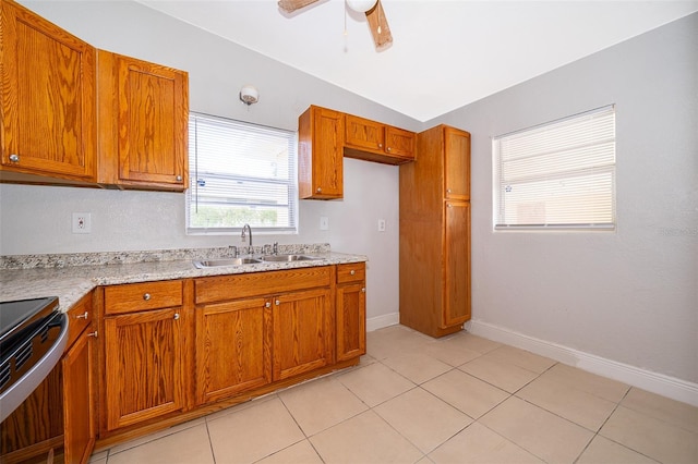 kitchen with ceiling fan, sink, light stone counters, vaulted ceiling, and light tile patterned floors