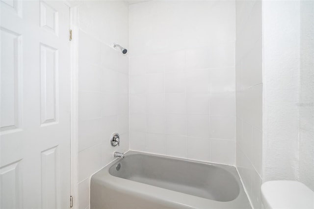 bathroom featuring tiled shower / bath combo and toilet