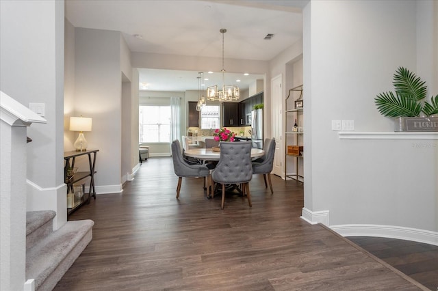 dining area with dark hardwood / wood-style flooring and an inviting chandelier