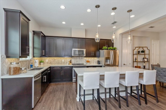 kitchen with hanging light fixtures, a center island, stainless steel appliances, and dark hardwood / wood-style floors