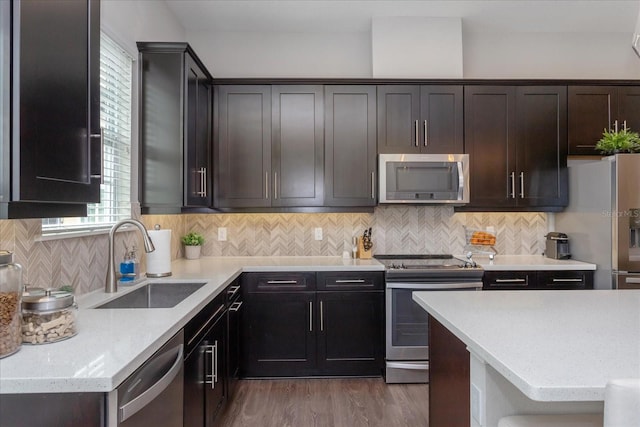 kitchen featuring hardwood / wood-style floors, sink, decorative backsplash, dark brown cabinets, and stainless steel appliances