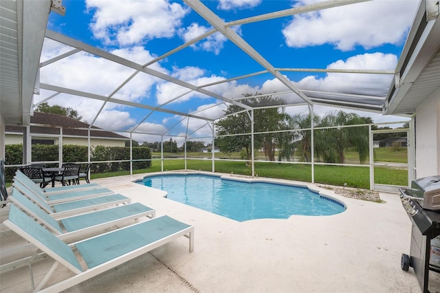 view of pool with a patio, a yard, and glass enclosure