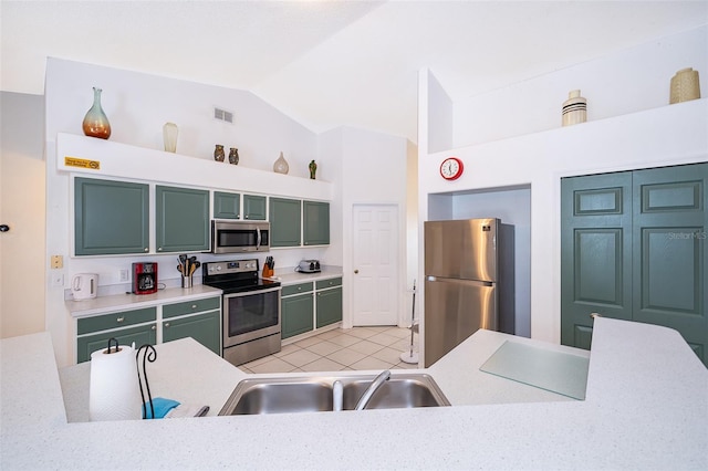 kitchen featuring appliances with stainless steel finishes, sink, vaulted ceiling, light tile patterned floors, and green cabinets