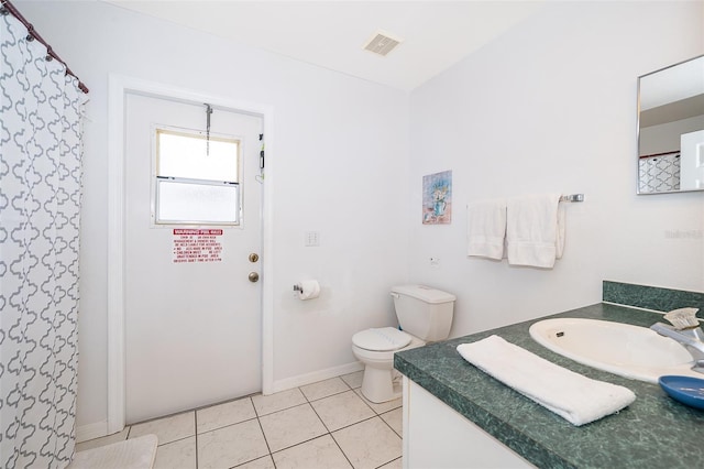 bathroom with toilet, vanity, and tile patterned flooring