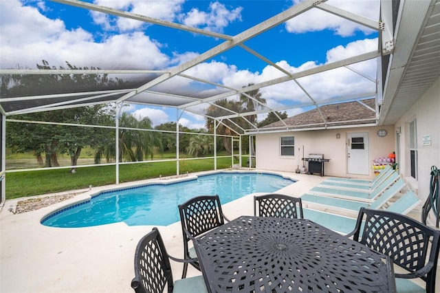 view of swimming pool with a lanai, a patio area, a grill, and a lawn