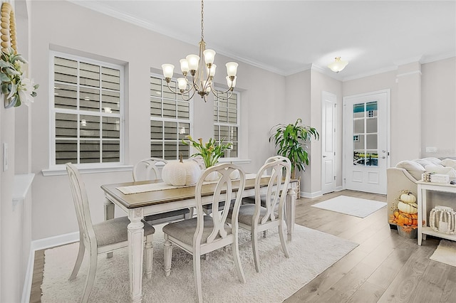 dining room with crown molding, light hardwood / wood-style floors, and an inviting chandelier