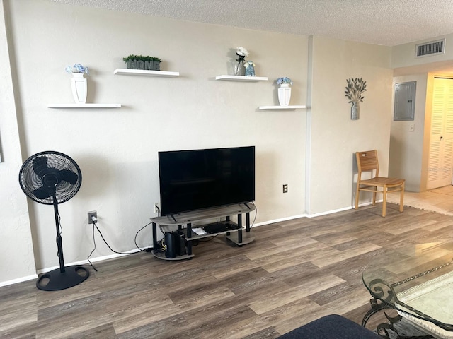 living room featuring wood-type flooring, a textured ceiling, and electric panel