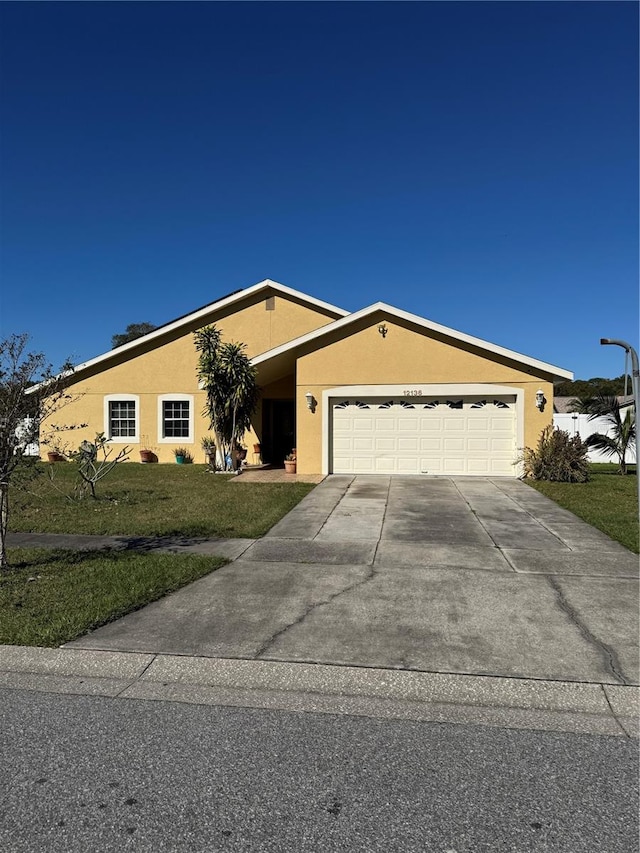 ranch-style house featuring a garage and a front lawn