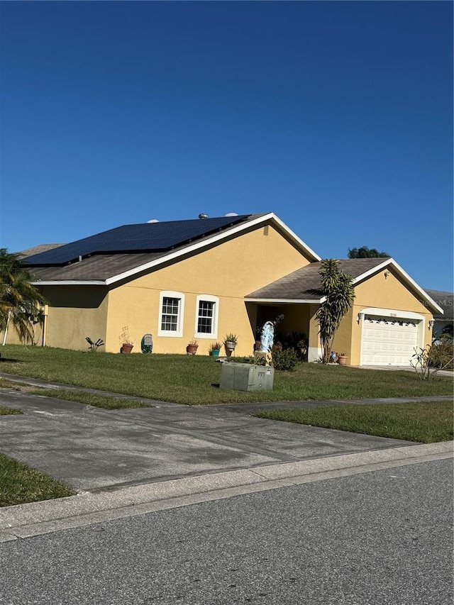 ranch-style home featuring a front yard, solar panels, and a garage