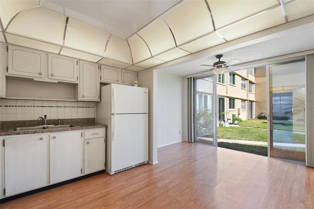 kitchen featuring backsplash, sink, white refrigerator, light hardwood / wood-style floors, and white cabinetry