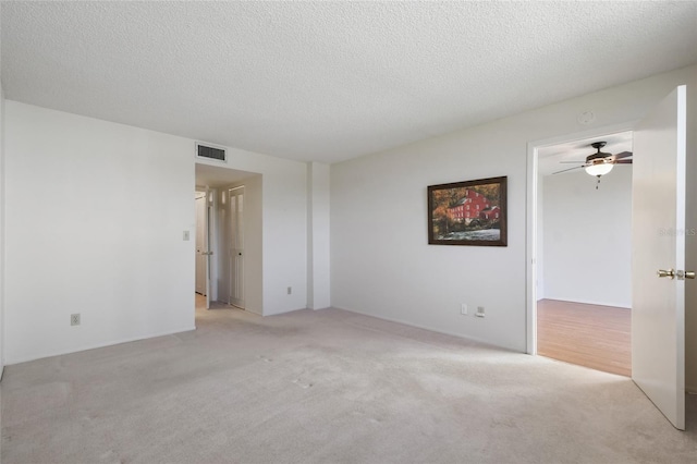 empty room featuring light carpet, a textured ceiling, and ceiling fan