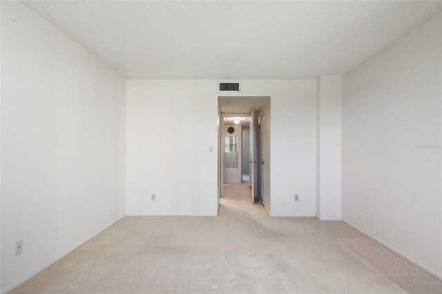 spare room featuring a textured ceiling and light carpet