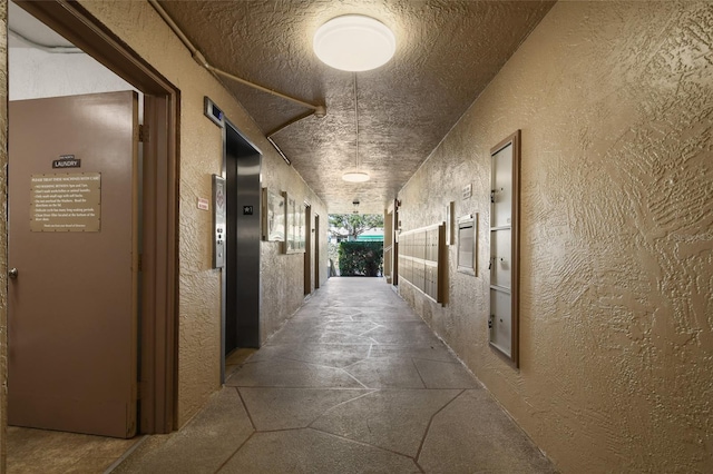 hall featuring a textured ceiling and elevator