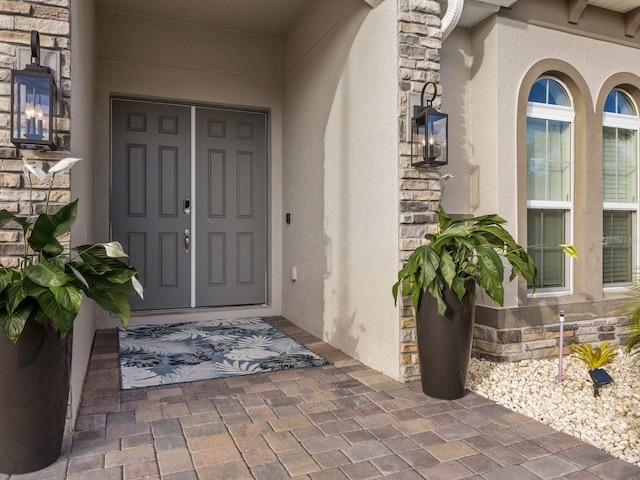 view of exterior entry featuring stone siding and stucco siding