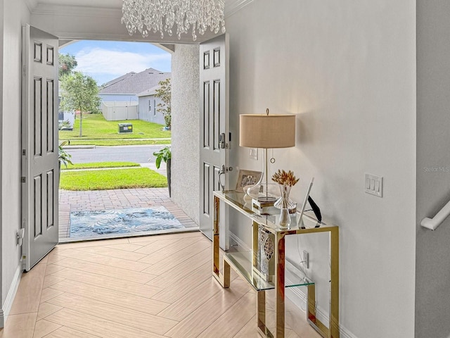 entrance foyer with an inviting chandelier, baseboards, and ornamental molding