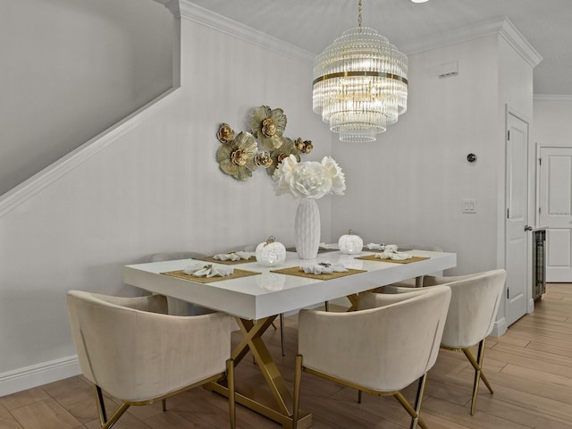 dining room with a notable chandelier, ornamental molding, baseboards, and wood finished floors