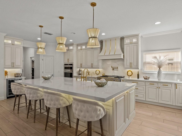 kitchen featuring premium range hood, visible vents, tasteful backsplash, wine cooler, and appliances with stainless steel finishes