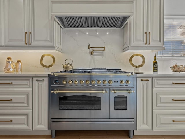 kitchen featuring double oven range, white cabinetry, exhaust hood, and light countertops