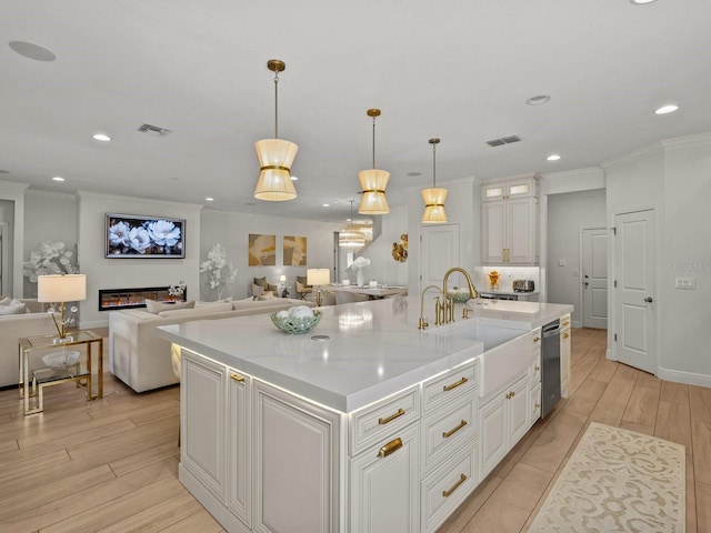 kitchen with visible vents, white cabinetry, a sink, stainless steel dishwasher, and crown molding