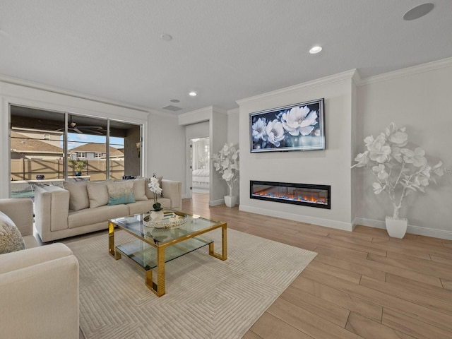 living room featuring a glass covered fireplace, crown molding, wood finished floors, and baseboards