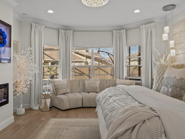 bedroom with a glass covered fireplace, recessed lighting, crown molding, and wood finished floors