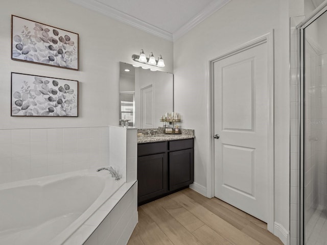 bathroom featuring ornamental molding, wood finished floors, tiled shower, a bath, and vanity