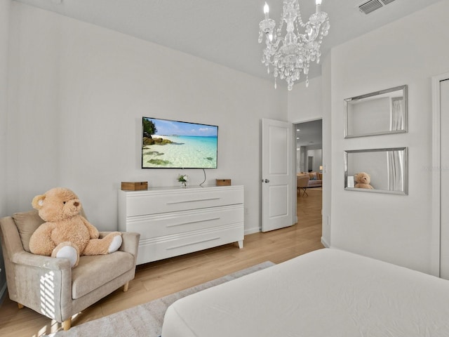 bedroom featuring visible vents, light wood-type flooring, and an inviting chandelier