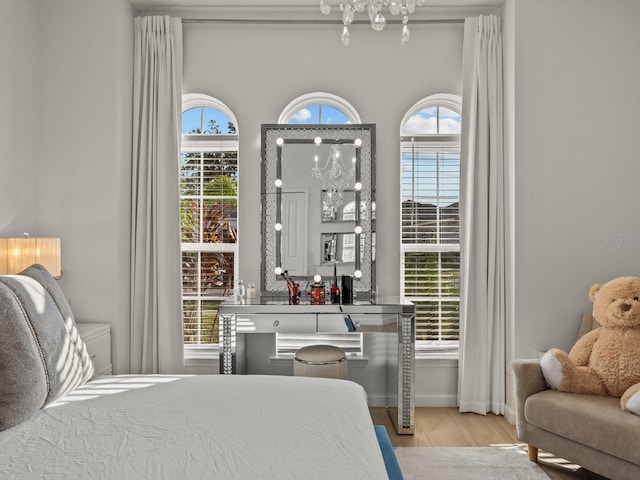 bedroom featuring multiple windows, wood finished floors, baseboards, and a chandelier